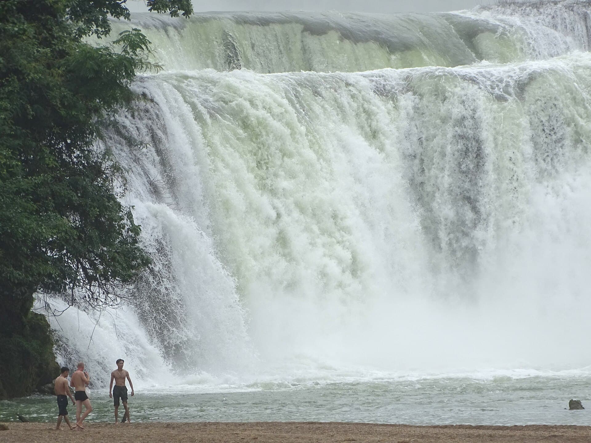 Ban Gioc waterfall spilling over tiered limestone steps on the Quay Son river — the headline stop on the eastern arm of the Cao Bang loop