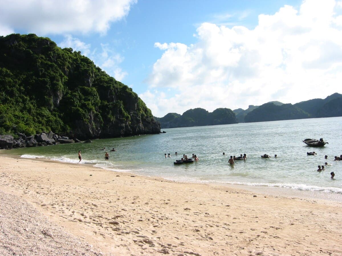Beach on Cat Ba Island with limestone karsts rising offshore in Lan Ha Bay