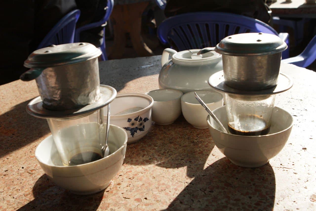 Vietnamese phin drip coffee filters in stainless steel sitting over glass cups at a Da Lat café — the country's signature slow-drip brewing method