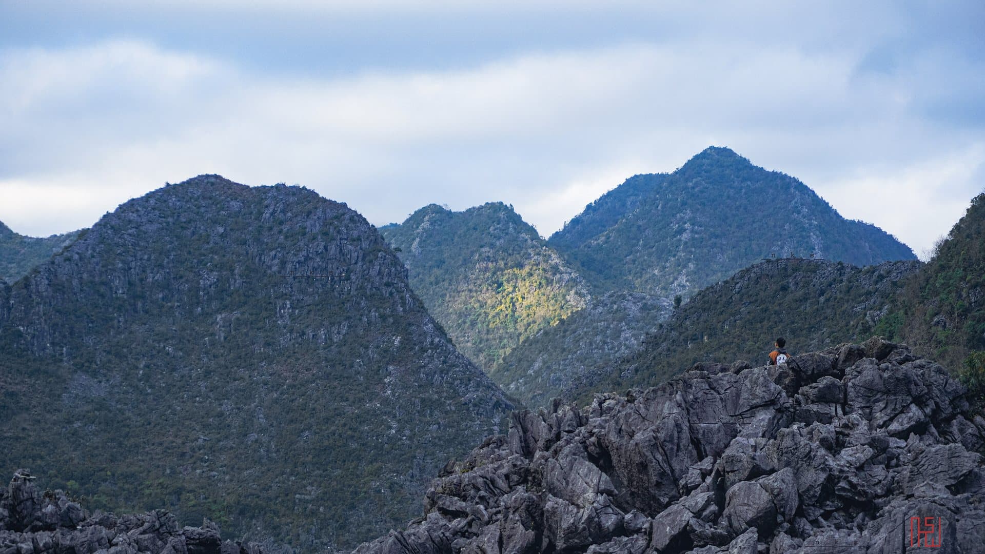 Jagged limestone peaks and grey karst rock of the Dong Van plateau in Ha Giang under drifting cloud, the high country the loop crosses