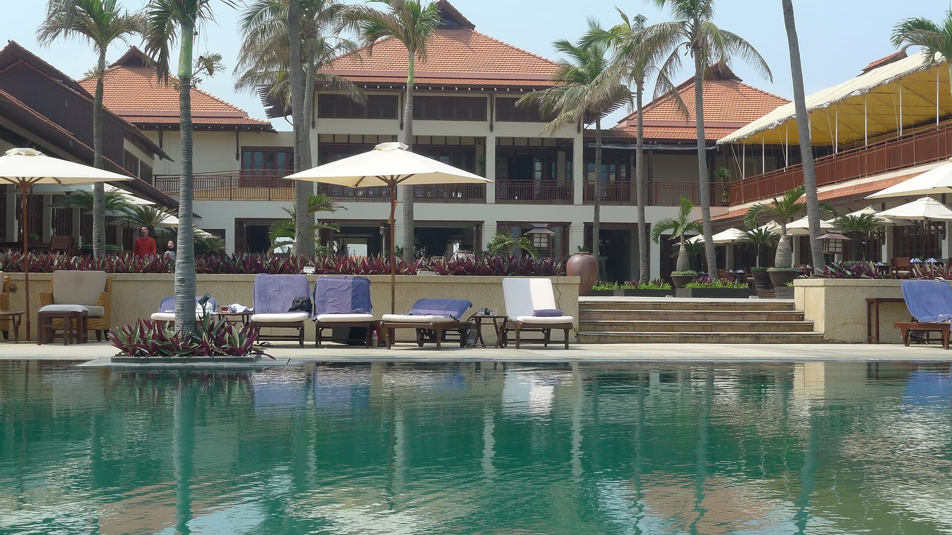 Sun loungers and white umbrellas around a palm-fringed resort pool on the Da Nang coast, the upper tier of the Vietnamese accommodation market this index prices