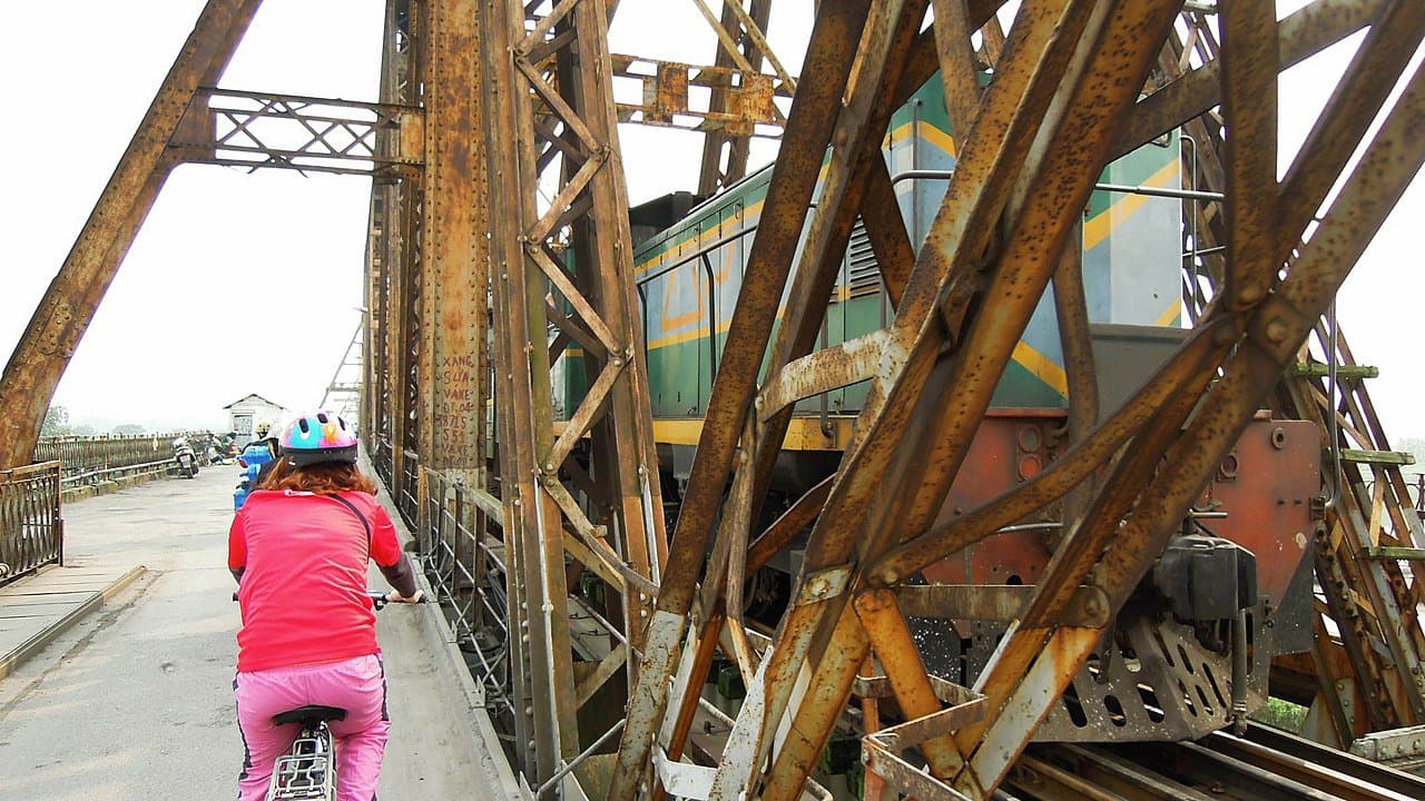 A cyclist and Vietnam Railways train sharing Long Bien Bridge in central Hanoi