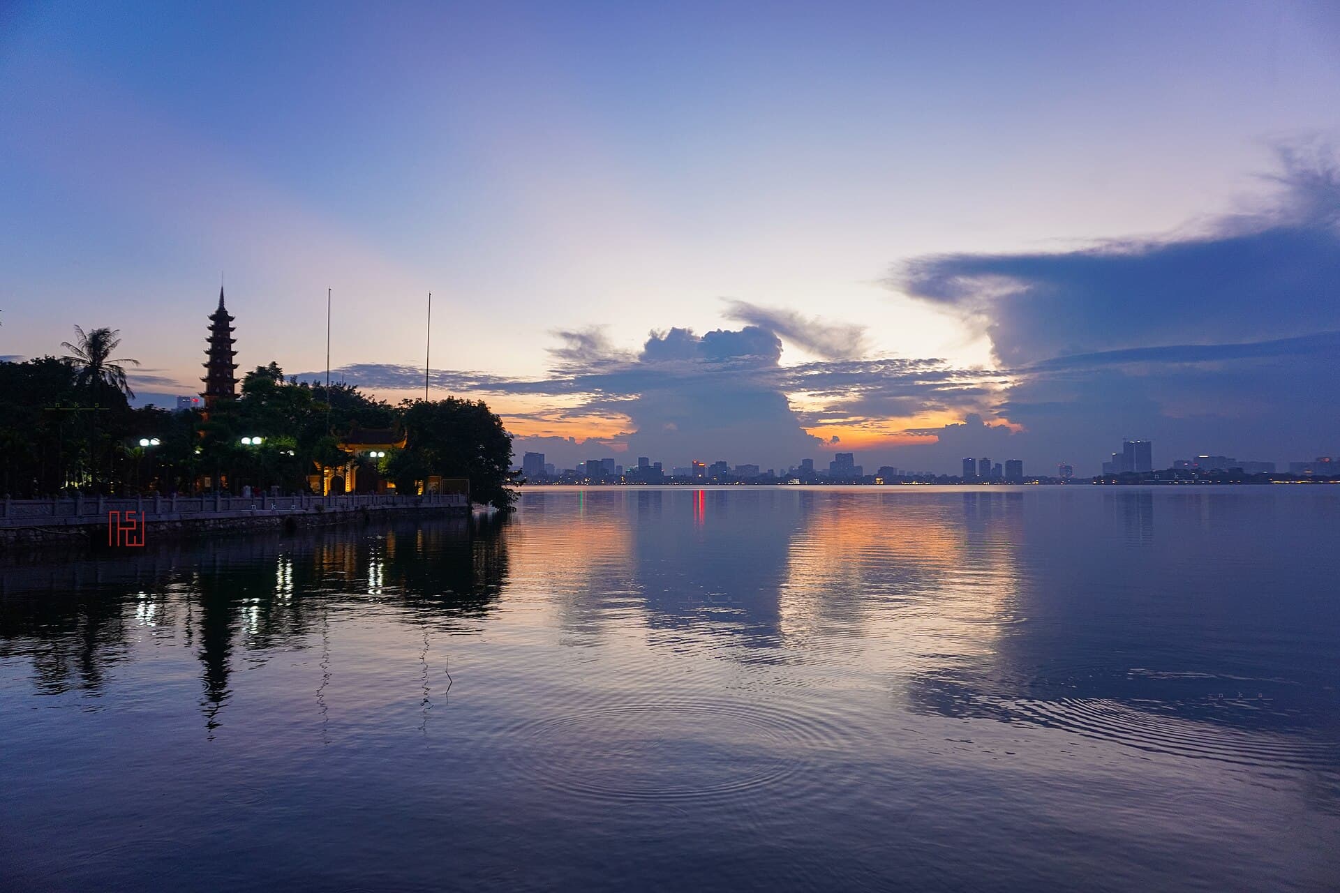 West Lake (Hồ Tây) at sunset with Tran Quoc Pagoda silhouetted against the Hanoi skyline — the quiet long-stay corner of Vietnam's capital