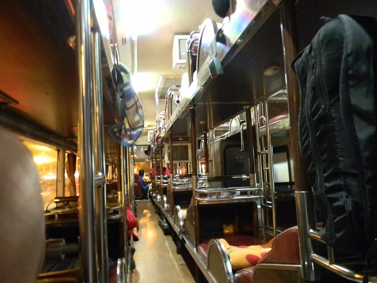 A Vietnamese sleeper-bus interior with tiered bunks lit by curtain lights