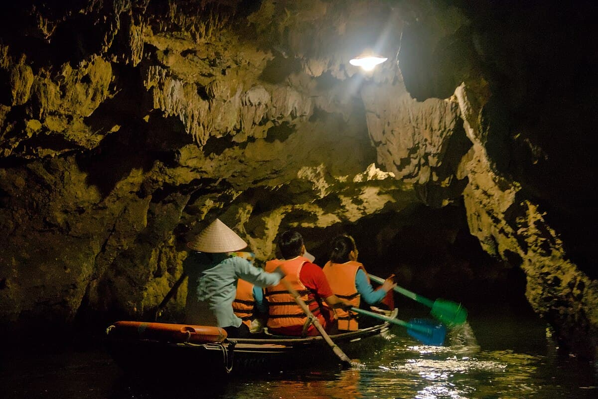 Boats gliding through a limestone cave tunnel in Trang An