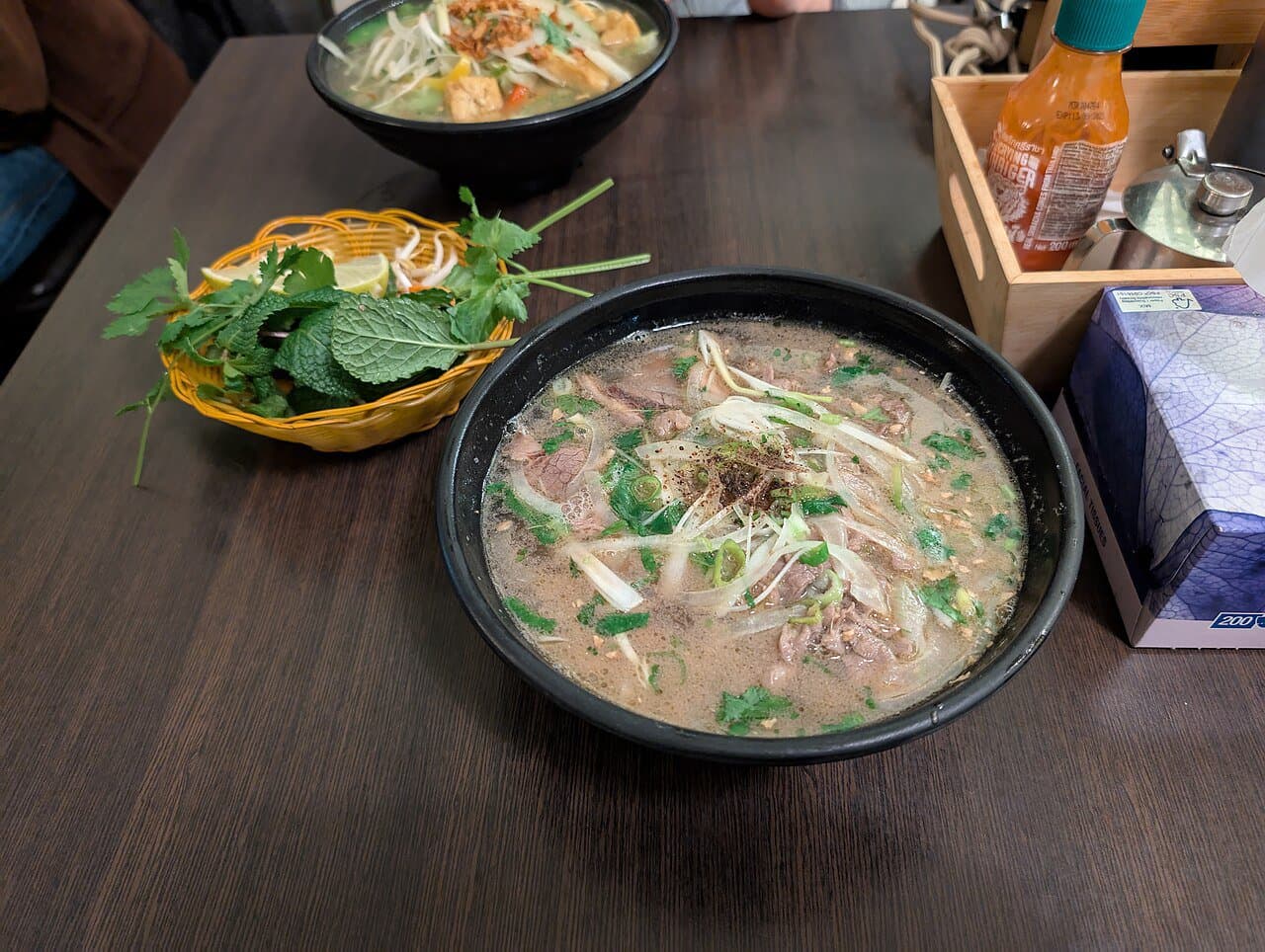 A steaming bowl of Hanoi pho bo with chopsticks — the city's signature dish and benchmark street-food spend