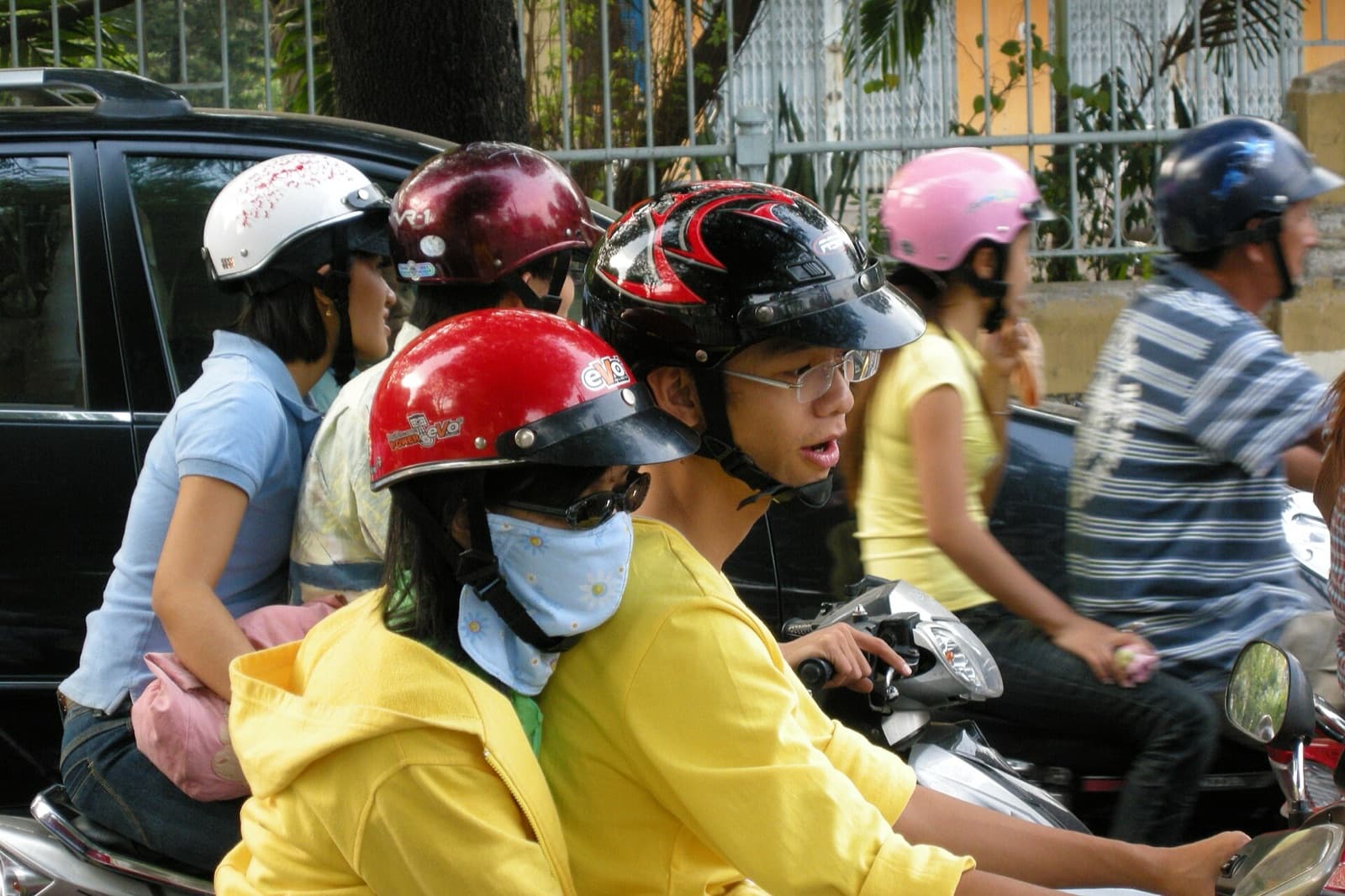 Helmeted riders packed shoulder to shoulder in Ho Chi Minh City motorbike traffic, several carrying a pillion passenger — the two-wheeled market GrabBike fares are set in
