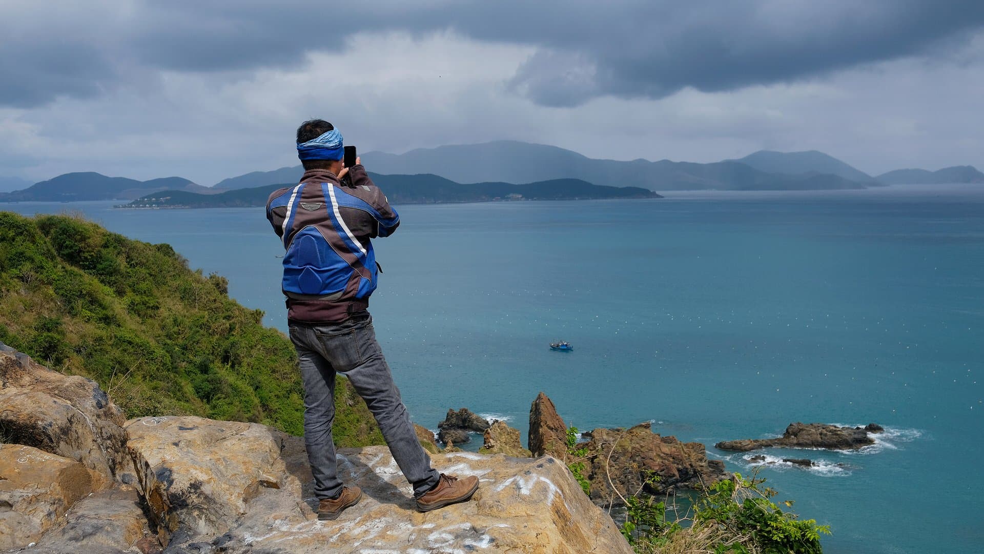 A traveller photographs the bay from a rocky headland on the Vietnamese coast, the kind of stop an independent trip is built around